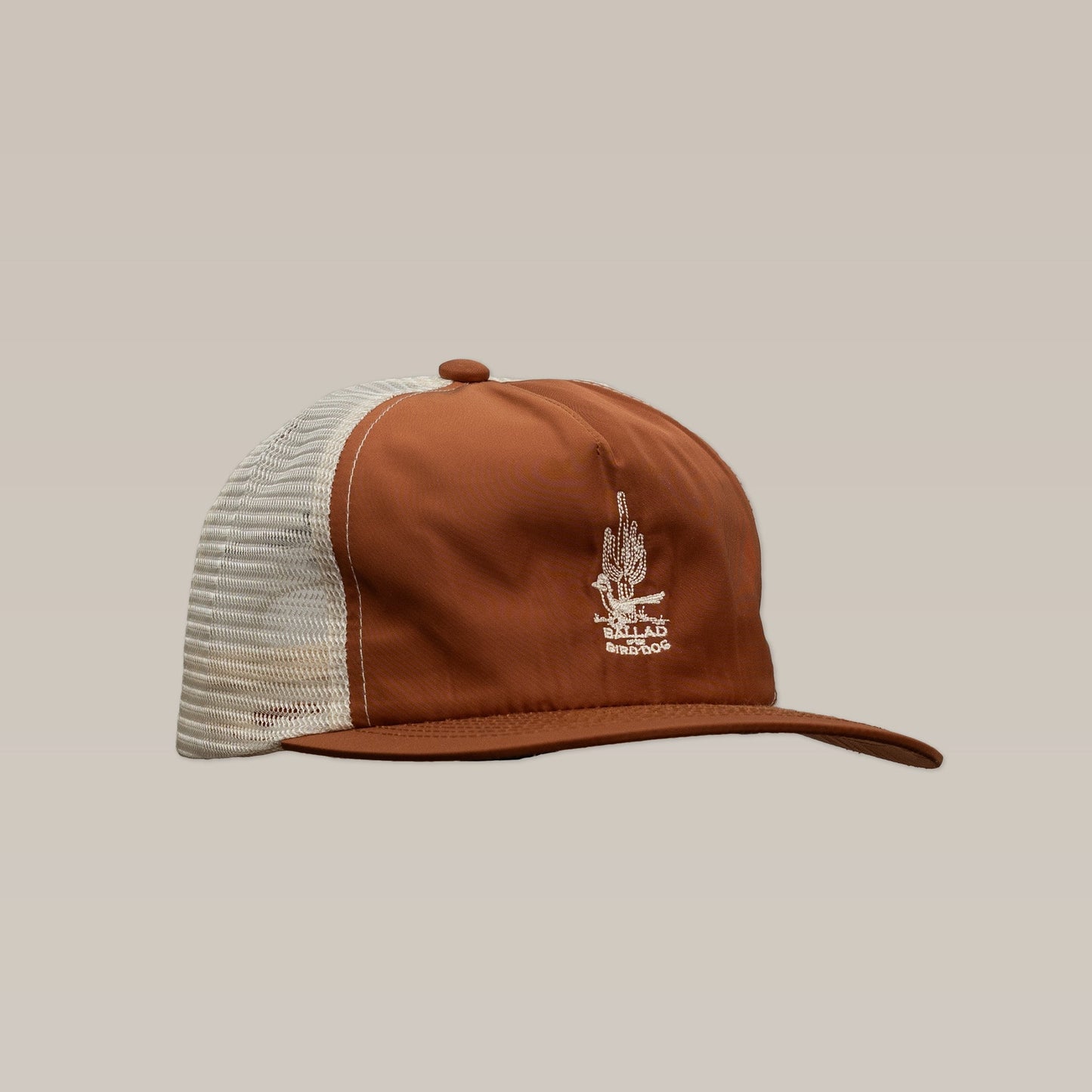 The Shop Hat | Roadrunner Saguaro by Ballad of The Bird Dog is a brown and white mesh trucker hat featuring an embroidered desert motif, shown against a neutral background.