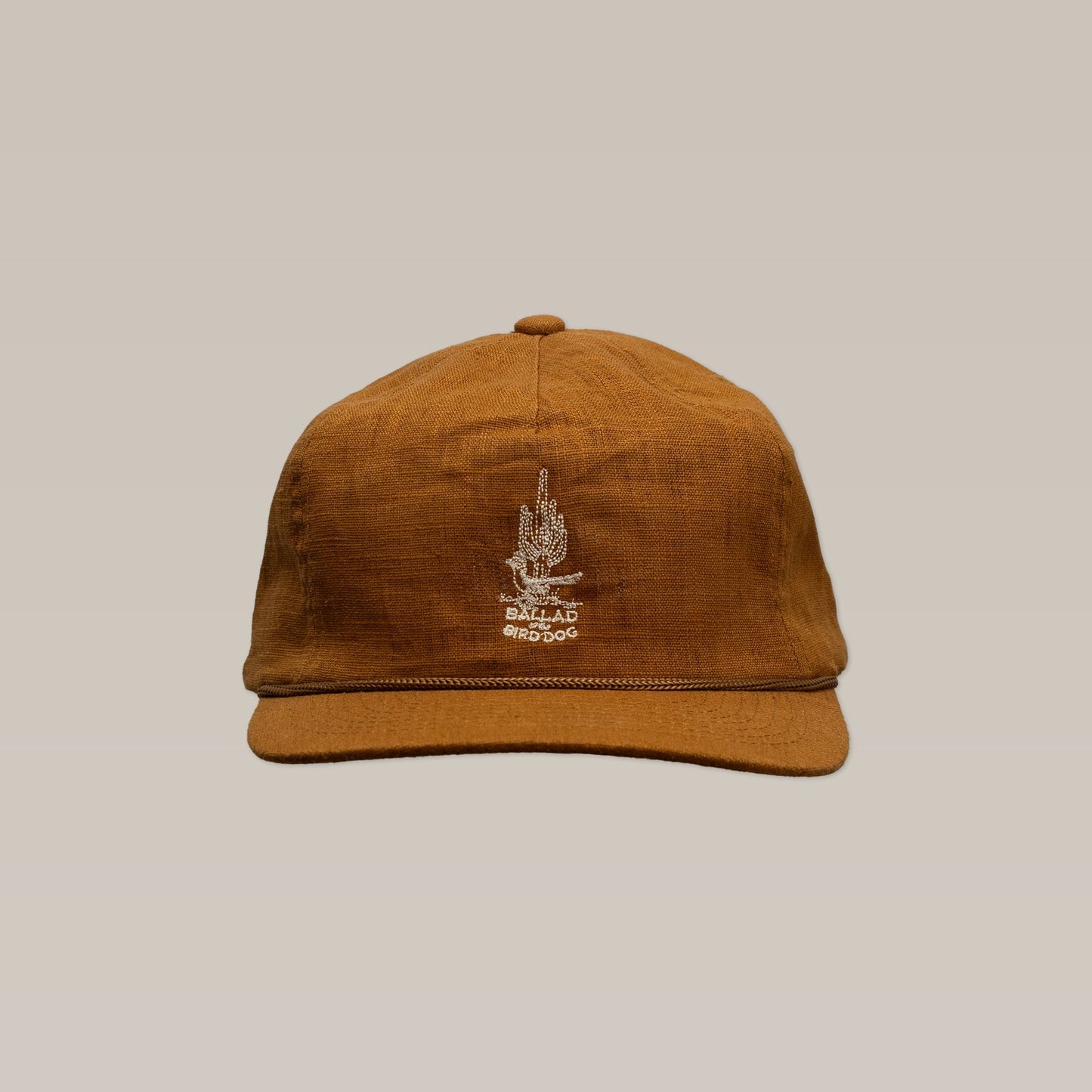 The Shop Hat | Roadrunner Saguaro by Ballad of the Bird Dog features an embroidered white design and text on the front, shown against a plain beige background.