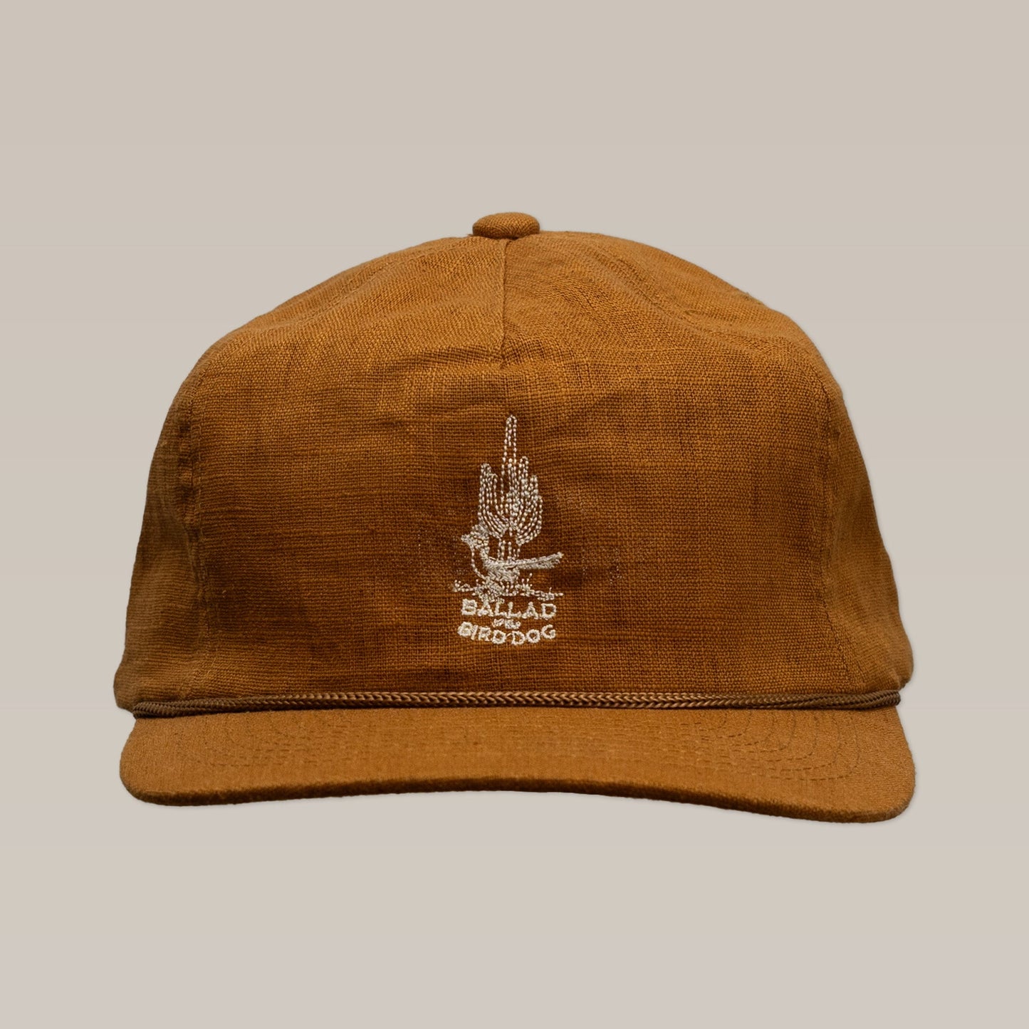 The Shop Hat | Roadrunner Saguaro by Ballad of the Bird Dog features brown fabric, a white embroidered plant, and "BALLAD BIRD DOG" on the front—perfect for Southwest desert vibes, shown against a beige background.
