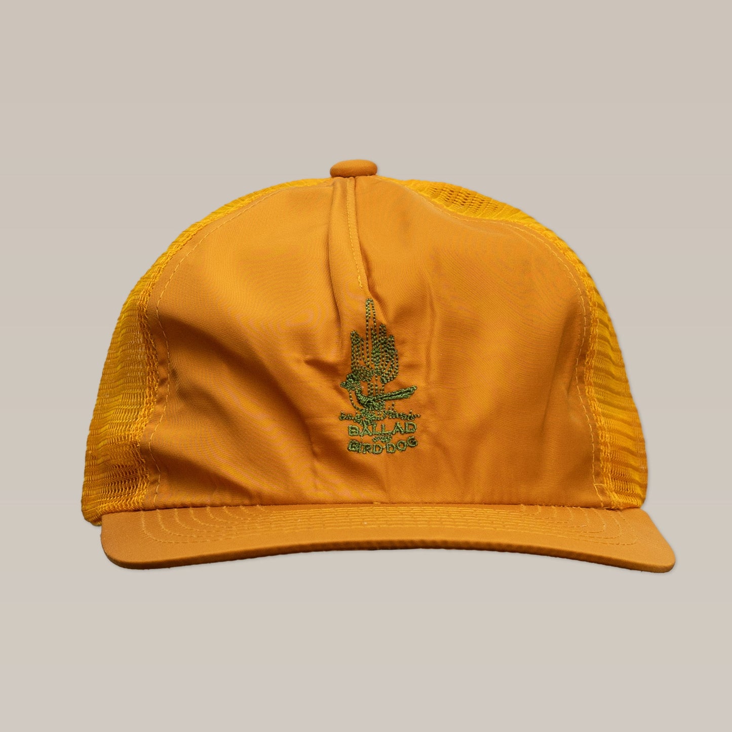 The Ballad of the Bird Dog “Shop Hat | Roadrunner Saguaro” is a yellow mesh trucker hat with a flat brim and green embroidered desert design—perfect for Southwest-inspired, sunny adventures. Shown on a plain background.