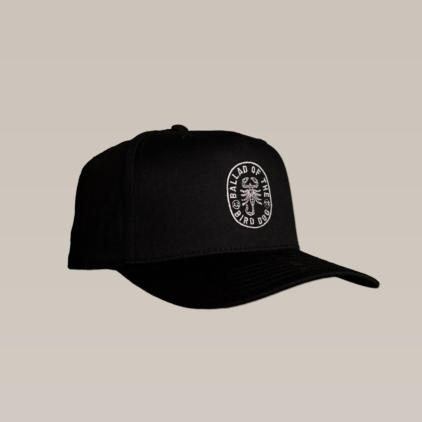 The Shop Hat | Scorpion by Ballad of the Bird Dog is a black baseball cap with a curved brim, featuring a white embroidered "BALLAD OF THE BIRD DOG" patch and bird dog graphic—part of our exclusive Desert Collection.