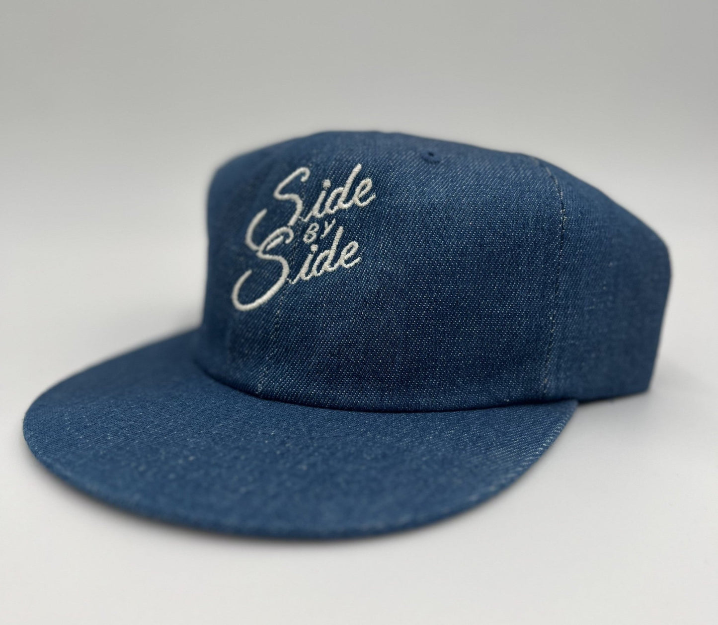 The Ballad of the Bird Dog Shop Hat | Side by Side features blue denim and white embroidered text on the front, celebrating bird dog companionship—crafted for quality and lasting style.