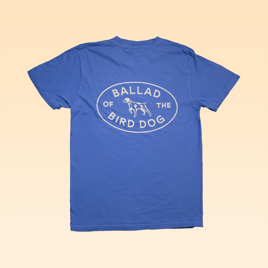 The Ballad of the Bird Dog Shop Shirt features a blue Bird Dog Emblem and an oval back logo reading "Ballad of the Bird Dog" with a dog line drawing—perfect for showing your bird dog pride in Downtown Brenham.