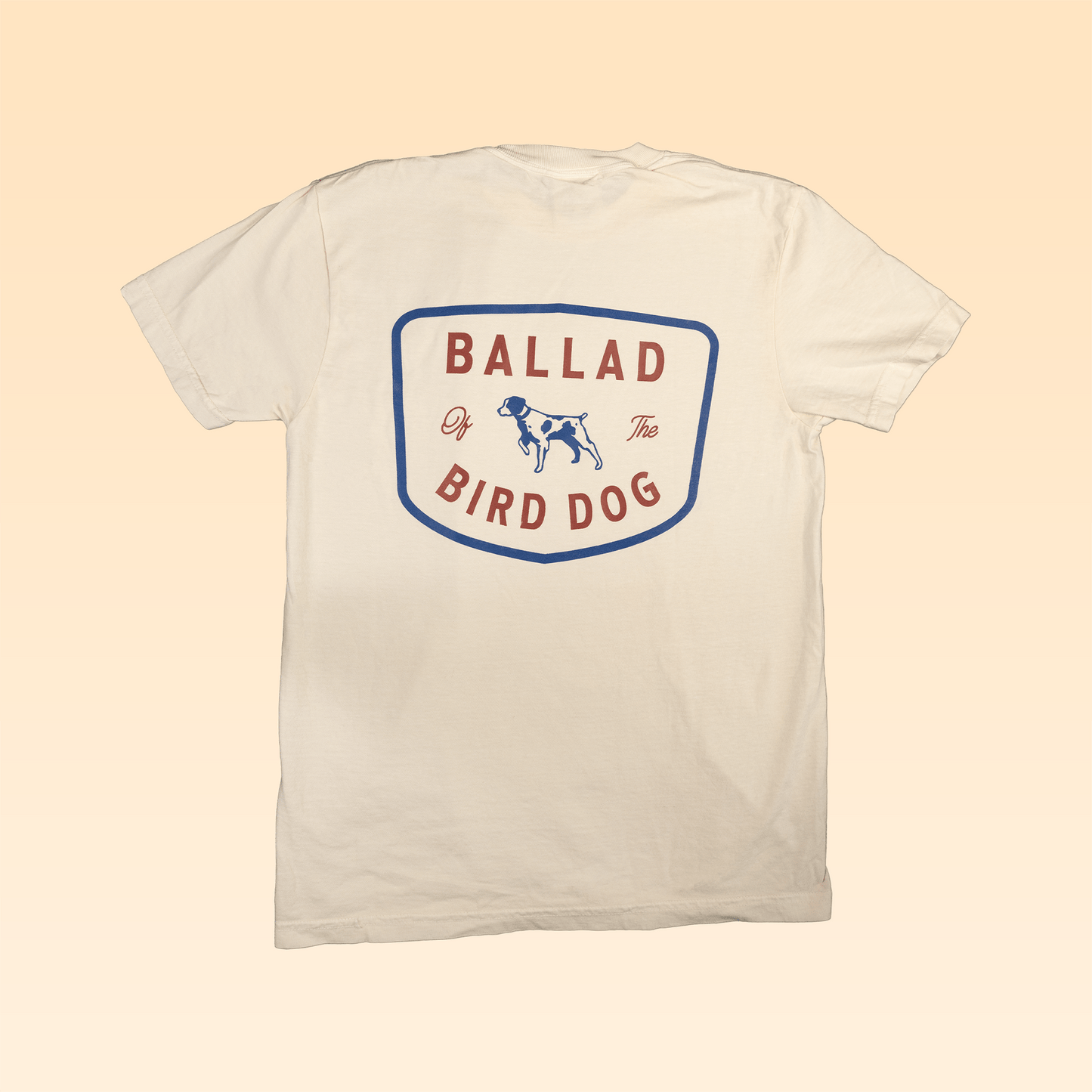 The Shop Shirt | Bird Dog Legend by Ballad of the Bird Dog features a bold shield graphic with an illustrated dog on the back—ideal for fans of Americana apparel and vintage hunting shirt styles.