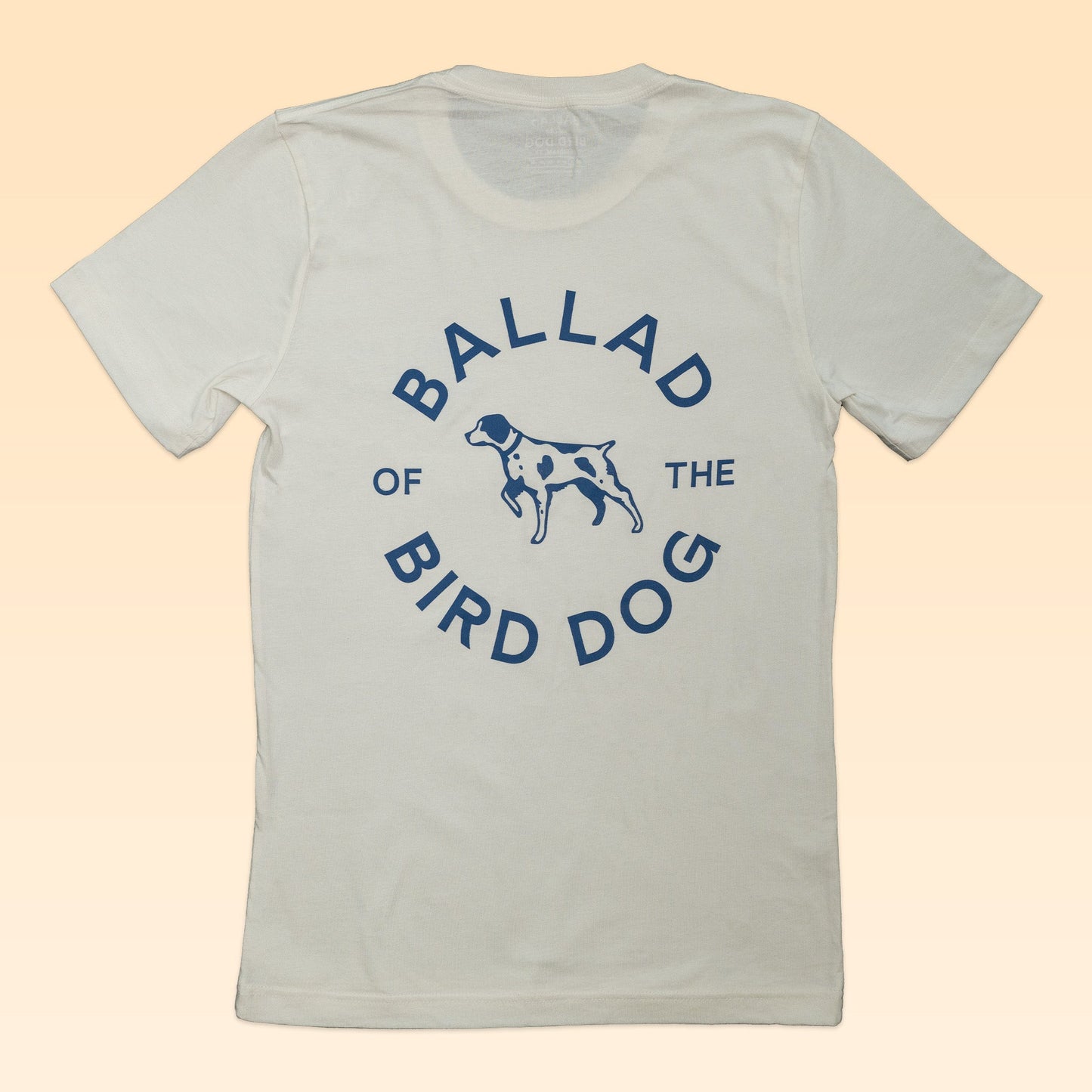 The Shop Shirt | Circle Clubhouse Tradition by Ballad of the Bird Dog features a white tee with blue "Ballad of the Bird Dog" text and a central bird dog graphic, perfect for fans of timeless circle logo shirt styles.