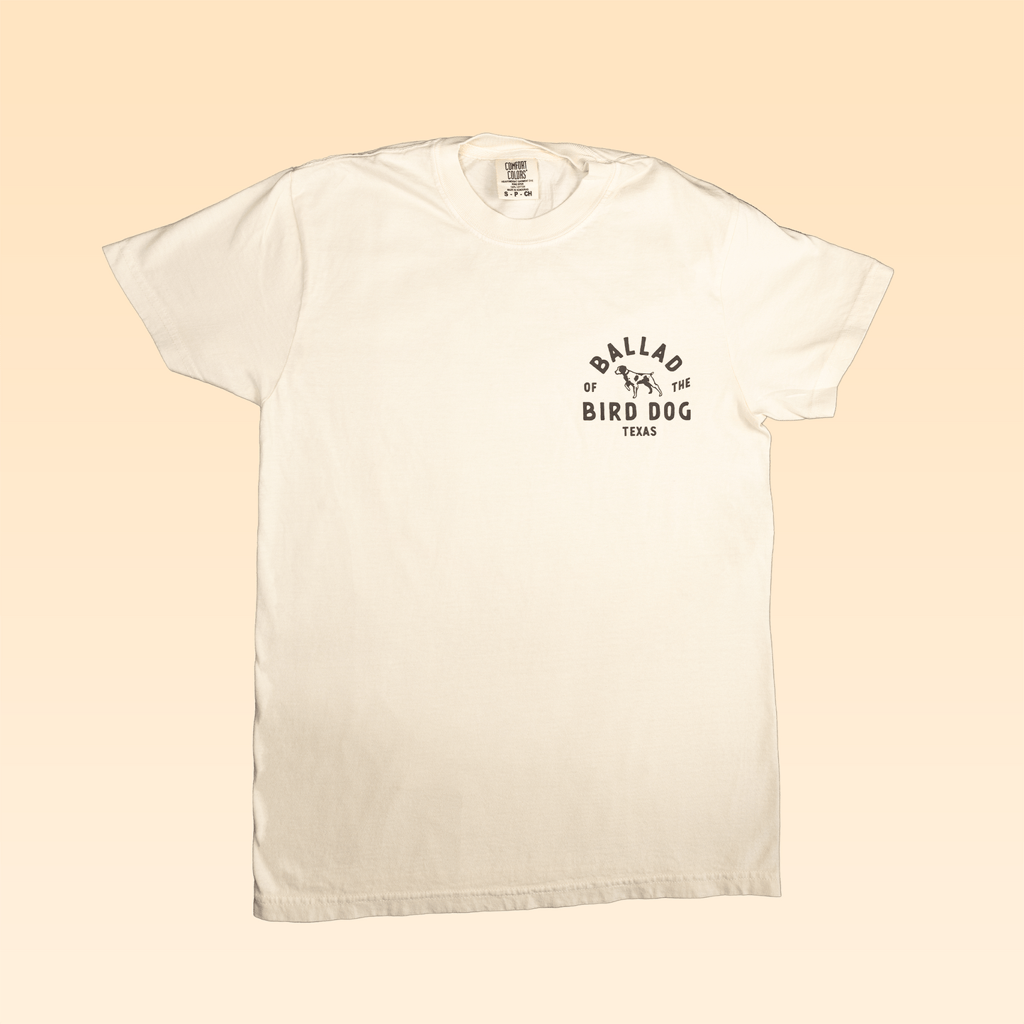 The Ballad of the Bird Dog Shop Shirt | Field Companion is a white shirt featuring “Ballad of the Bird Dog Texas”, a small dog graphic, and an original design patch on the left chest.