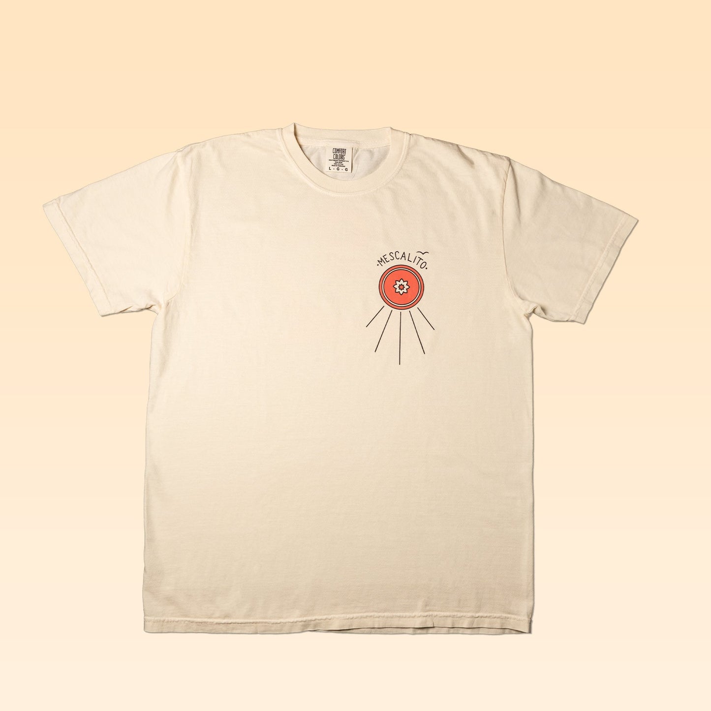 The Shop Shirt | Hawks by Mescalito Coffee is a cream T-shirt featuring a small orange circle and "ESCALITE" on the left chest, inspired by the relaxed West Texas vibe.