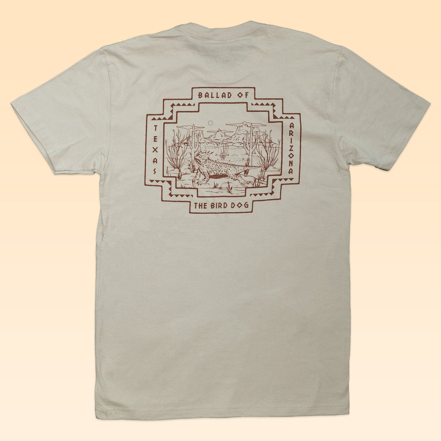 The Shop Shirt | Horny Toad by Ballad of the Bird Dog features beige fabric with a brown desert landscape design on the back and is part of the Desert Scenes Collection—perfect for fans of iconic horny toad shirt styles.