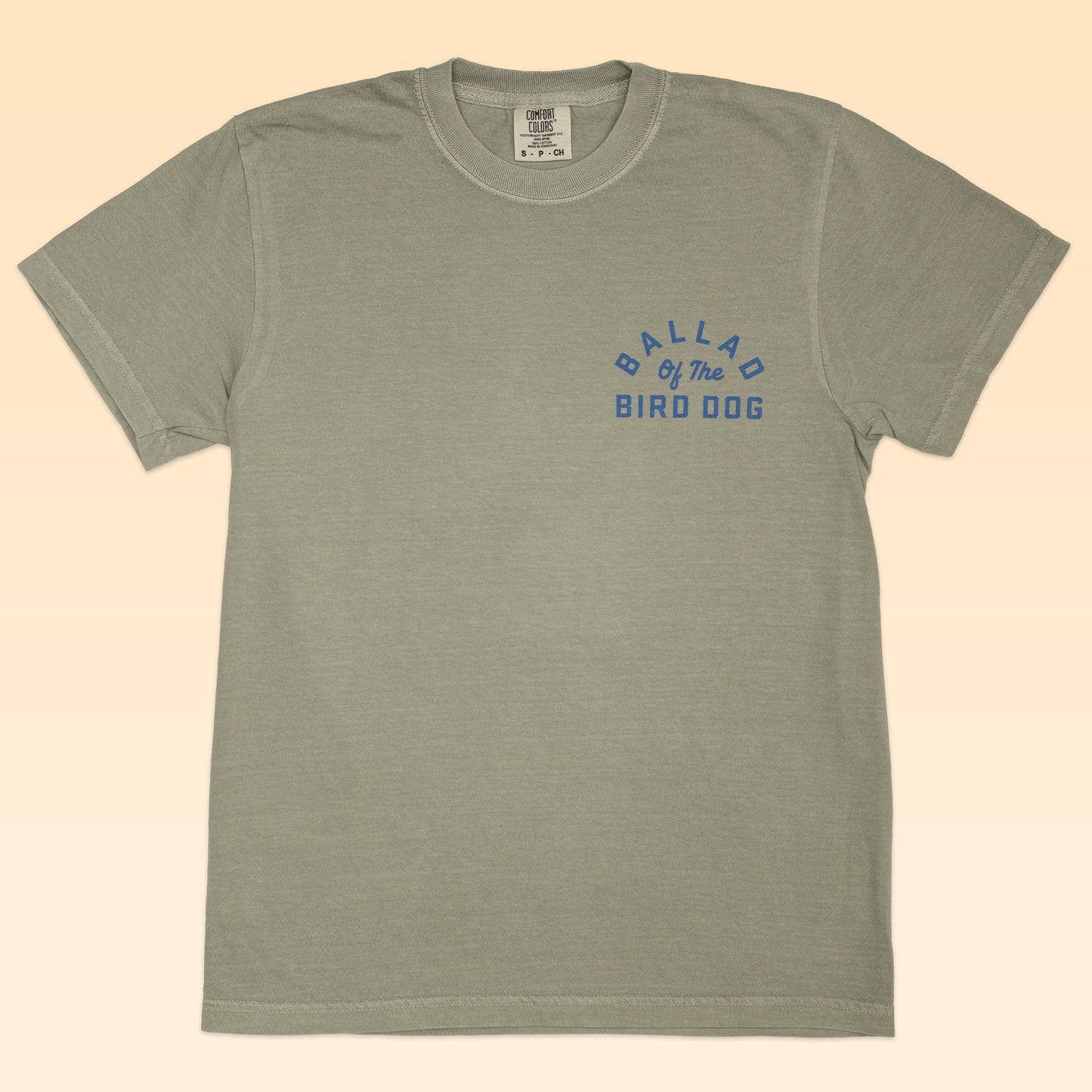 Light gray Ballad of the Bird Dog Shop Shirt with short sleeves and a blue "BALLAD OF THE BIRD DOG" print on the upper left chest, featuring a subtle rattlesnake oval logo from the Desert Collection.
