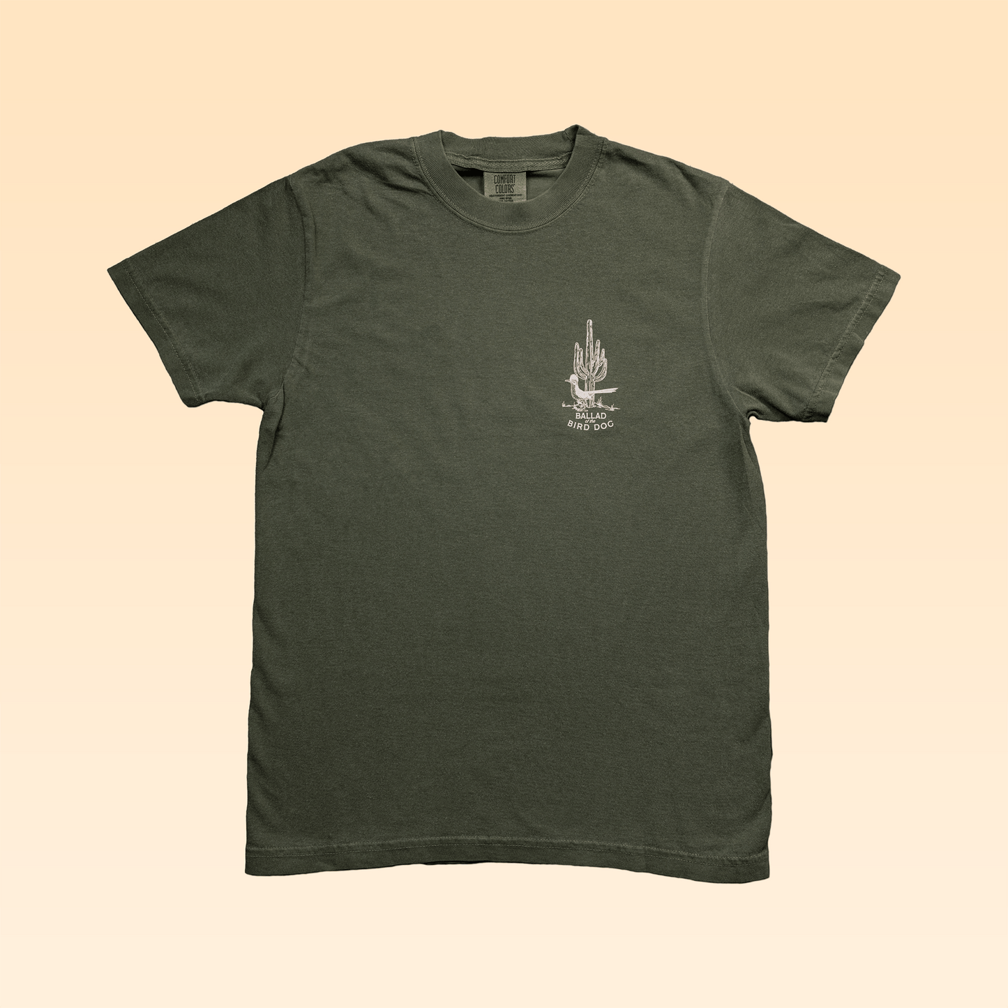 The Ballad of the Bird Dog Shop Shirt in olive green features a small white Roadrunner vs. Rattlesnake graphic and text on the left chest, shown against a plain light beige background.