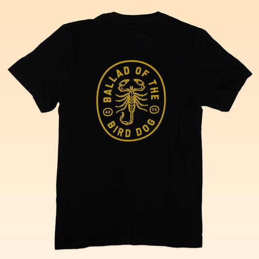 The Ballad of the Bird Dog Shop Shirt | Scorpion is a black tee from the Desert Scenes Collection, hand-printed with a yellow oval scorpion graphic and "Ballad of the Bird Dog" text on the back for bold desert style.