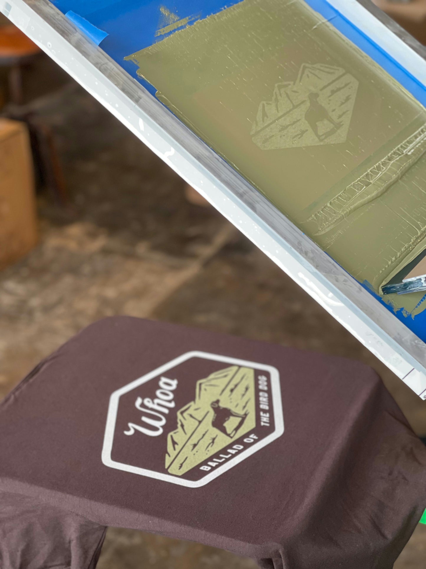 The Shop Shirt | Whoa by Ballad of the Bird Dog is a dark graphic tee featuring a "Whoa Ballad St. Est. 1996" design shown beneath a screen-printing frame with matching artwork.