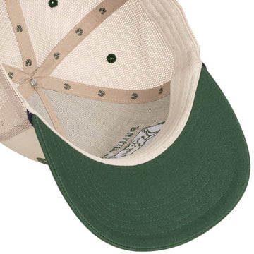 The Skinny Cows Hat by Sendero Provisions Co. is a beige mesh trucker hat with a green brim, shown from above to highlight its inside panel and stitching—ideal for relaxing after rounding up skinny cows.