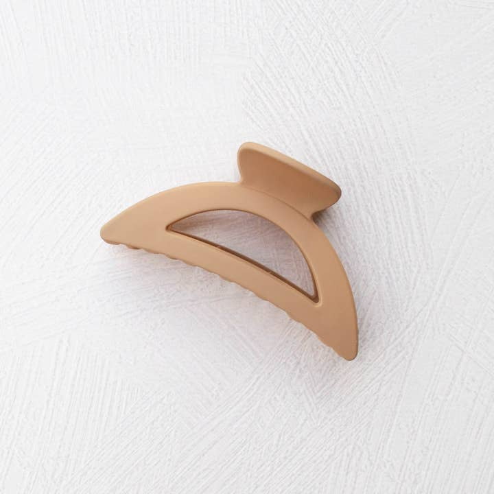 The Tiepology Solid Matte Dix Cup Hair Clip features a tan, matte finish and semicircular design. At 2 inches, this acrylic claw clip is ideal for everyday styling and looks elegant on any white textured surface.