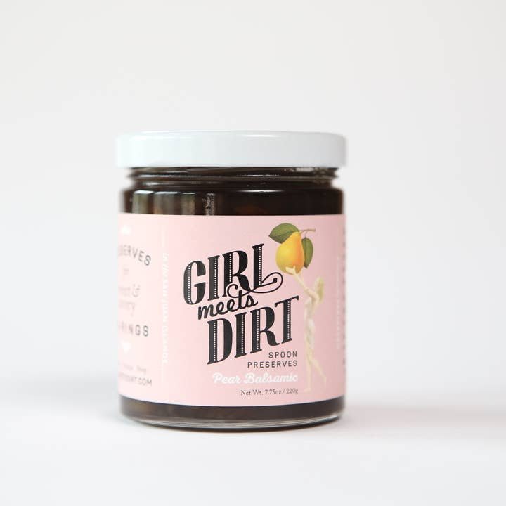 A glass jar with a white lid labeled “Spoon Preserves | Girl Meets Dirt,” from the brand Girl Meets Dirt, displays artisanal preserves against a plain white background.