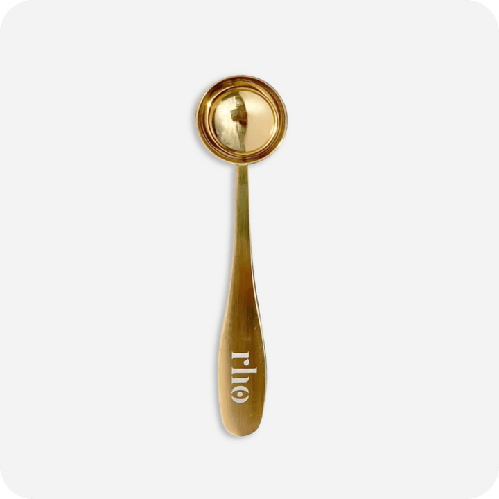 A gold-colored engraved serving spoon with "otto" on the handle, inspired by the Rho routine, rests on a white background—a chic twist on the classic Stainless Steel Serving Spoon by Rho Nutrition.
