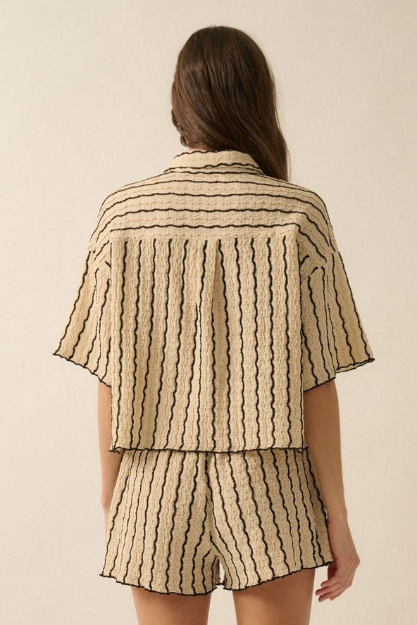 A woman faces away, wearing the Promesa USA Striped Textured Knit Button-Up with black wavy vertical stripes and matching shorts.