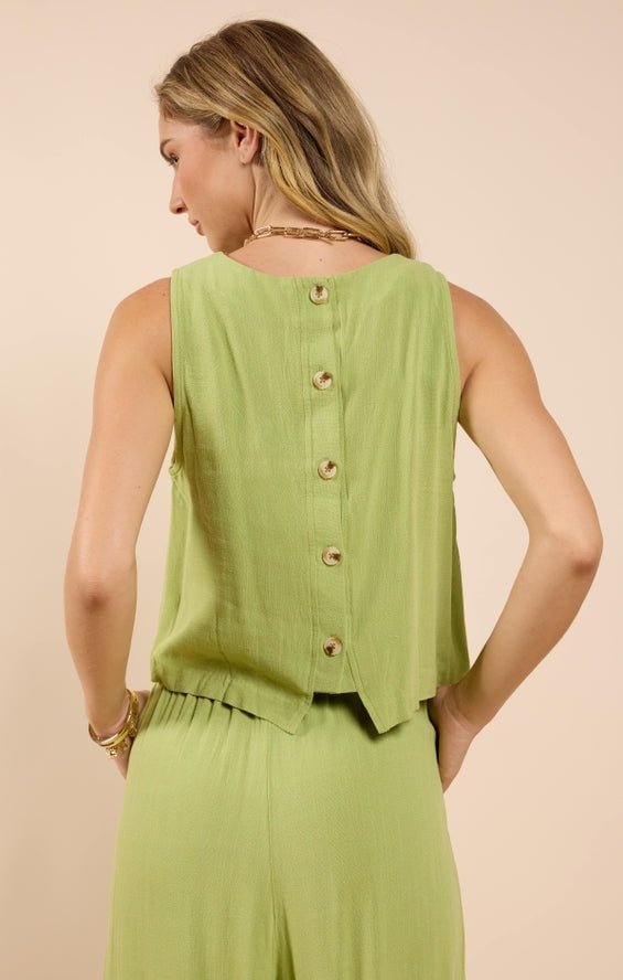 A woman models the Sugarloaf Linen Tank by Sadie And Sage—a sleeveless, light green rayon-linen top with button-back details—paired with matching pants. She faces away from the camera, ideal for small size women's collections.