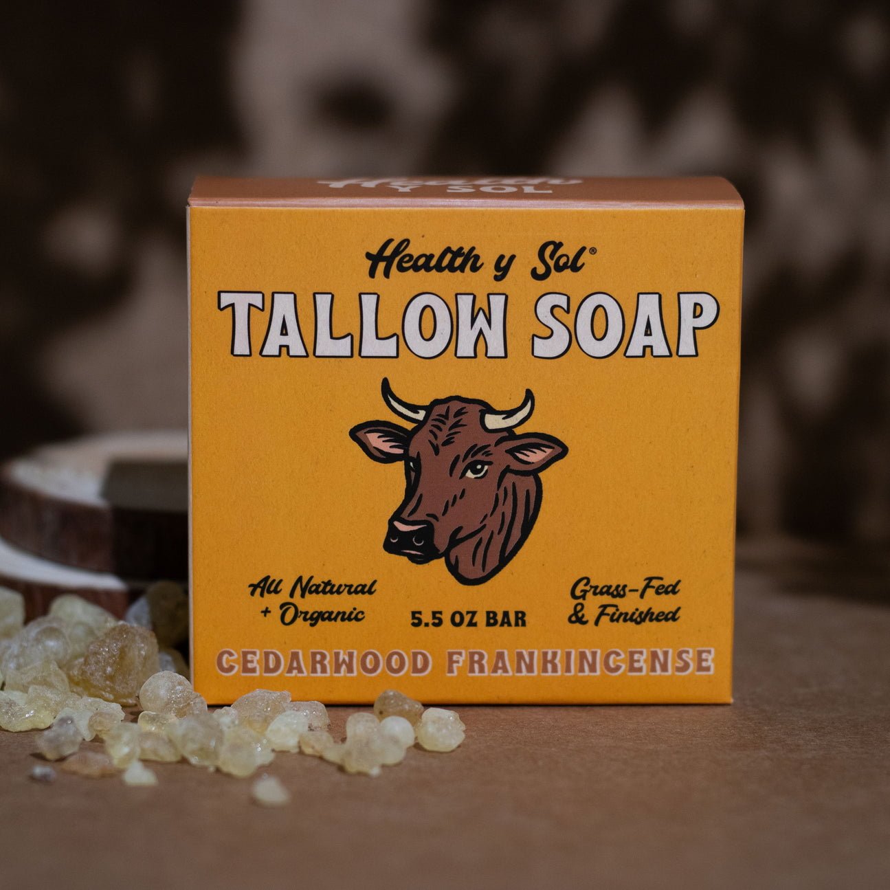 A box of Health y Sol Tallow Soap by Health y Sol, Cedarwood Frankincense scent, made with all natural, organic, grass-fed and finished ingredients to help reduce acne and soothe eczema, sits beside some resin pieces.
