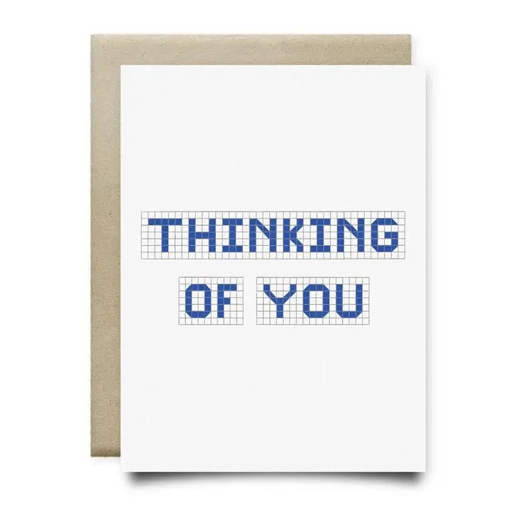 The "Thinking of you | Anvil Cards" A2 greeting card by Anvil Cards features "THINKING OF YOU" in blue block letters on a grid background, comes with a brown envelope, and is printed on sustainable linen paper.