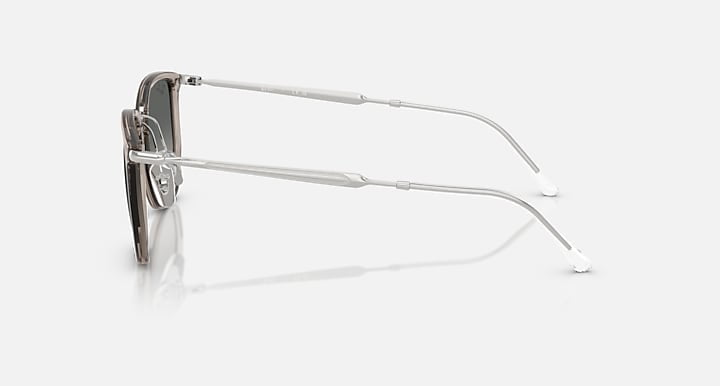 Side view of Ray-Ban Transparent Grey with Grey Gradient eyeglasses, featuring a transparent grey frame and thin silver metal arms, shown on a plain light background.