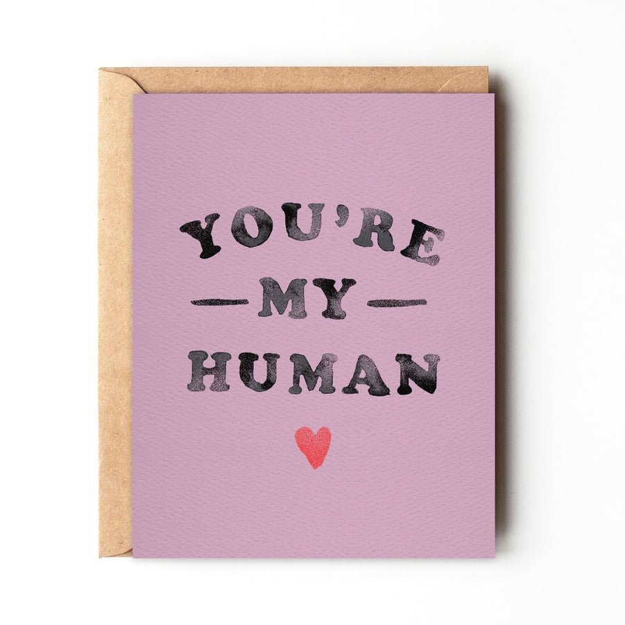 The "You're My Human" card by Daydream Prints is an eco-friendly, mauve greeting card featuring bold black text, a small red heart, retro hippie charm, and comes with a brown envelope.