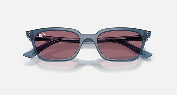 Ray-Ban Zaya sunglasses in light blue with pillow-shaped frames and violet lenses, shown against a plain white background.
