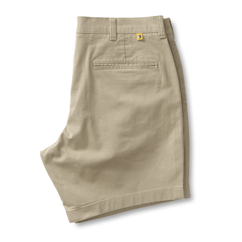 The Duck Head 7 in Gold School men's chino shorts come in beige khaki with belt loops, a back pocket, and a yellow logo patch above the pocket. They feature a comfortable 7" inseam.
