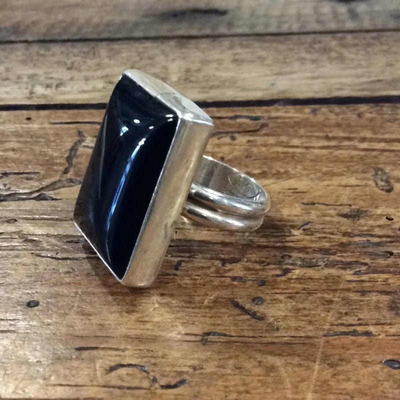 The Vintage Black Onyx Ring features a large rectangular stone set in sterling silver, shown on a wooden surface and available in size 7.5.