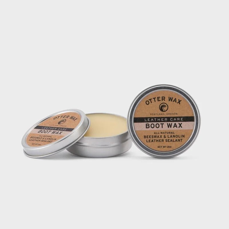 An open tin of Otter Wax Boot Wax shows the beeswax-based formula inside, with a closed tin beside it—ideal for natural leather care by Otter Wax.