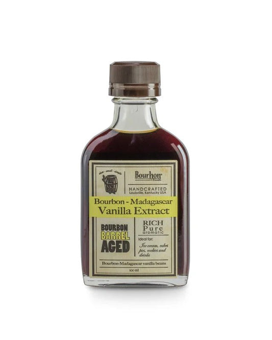 A small glass bottle of Bourbon Barrel Foods' Bourbon Barrel Aged Vanilla Extract, single-strength and handcrafted, features a brown cap and highlights its bourbon barrel aging.