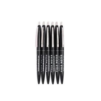 A row of six black Field Notes Click Pens, each with "FIELD NOTES" and extra text on the barrel, featuring smooth black ink, displayed against a white background.