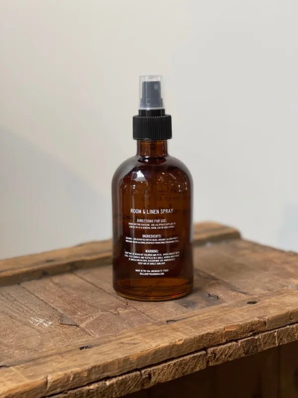 A bottle of Ballad of the Bird Dog's Dog Spray rests on a wood surface.
