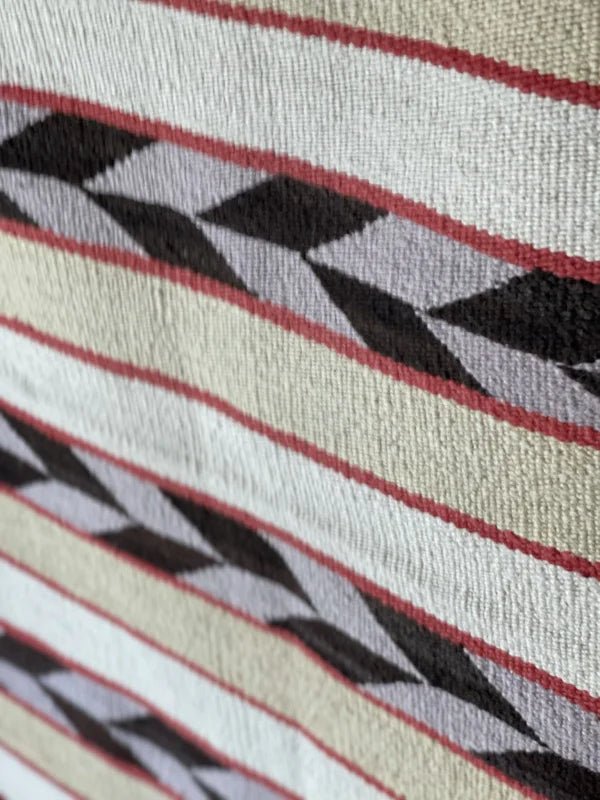 Close-up of a Double Saddle Blanket Circa 1940 by Vintage, featuring woven cream, black, and red geometric patterns with diagonal and horizontal lines inspired by arrow feathers.