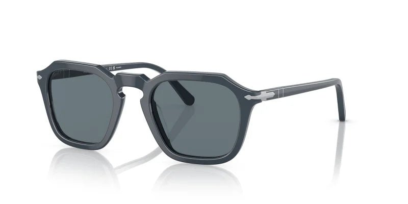 The Persol 0PO3292S Dusty Blue w/ Dark Polar sunglasses feature an angular bold acetate frame, dark polarized lenses, silver temple accents, and a keyhole bridge, displayed against a white background.