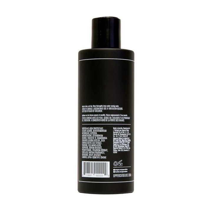 A black plastic bottle of Uppercut Deluxe Everyday Conditioner is shown from the back, with white text detailing product information, instructions, and ingredients. It contains olive leaf extract to provide added hydration.