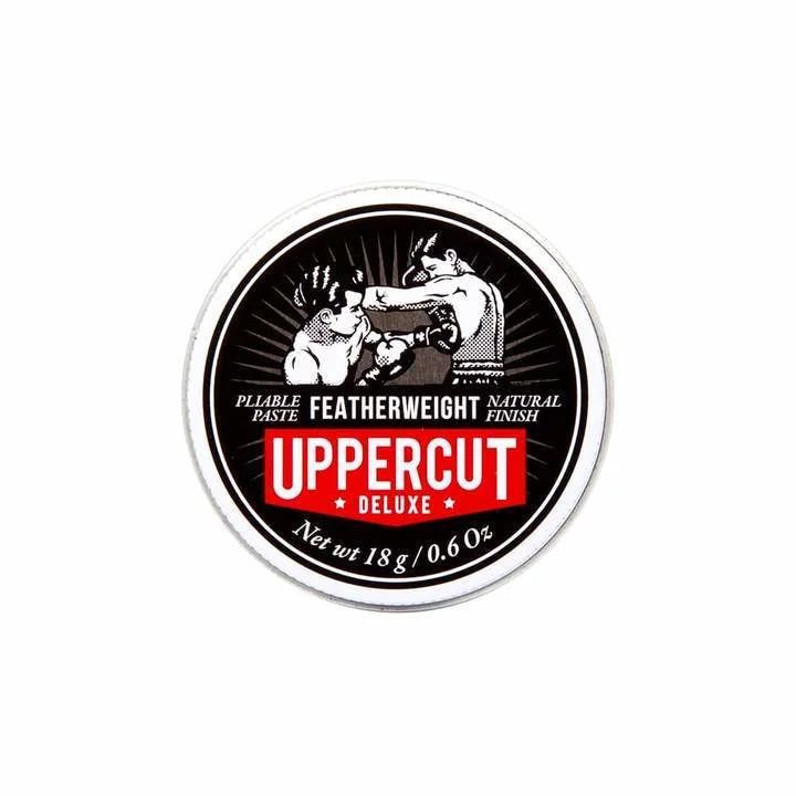 A round tin of Uppercut Deluxe Featherweight Paste featuring a black and white illustration of two boxers, product details, and an 18g net weight.