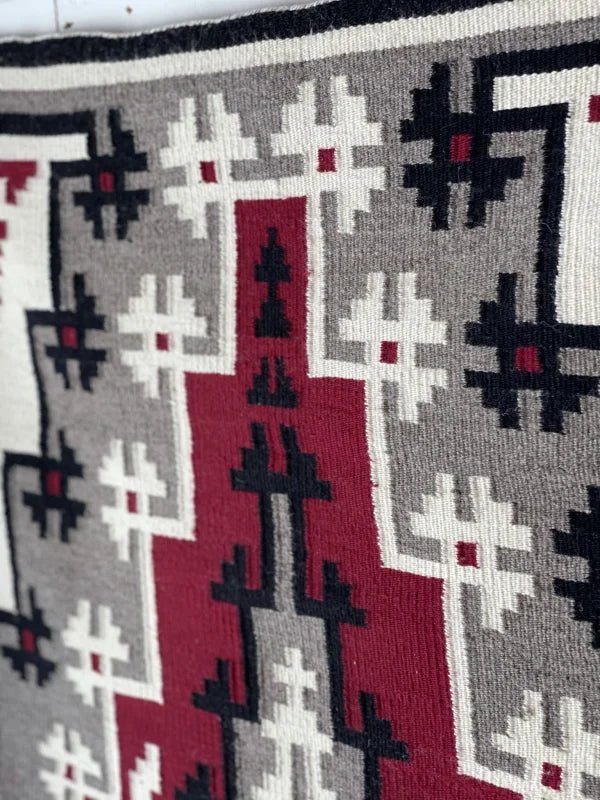 A close-up of the Ganado Rug Classic "Snowflake" CA 1980 by Vintage, featuring geometric patterns in red, black, white, and gray that showcase classic Ganado Navajo weaving style.