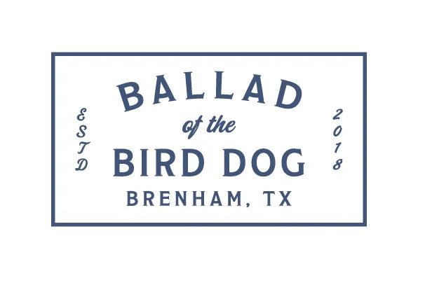 A white rectangular sign with blue text showcases the Ballad of the Bird Dog Gift Card—the ideal gift from Ballad of the Bird Dog, delivered easily by email.