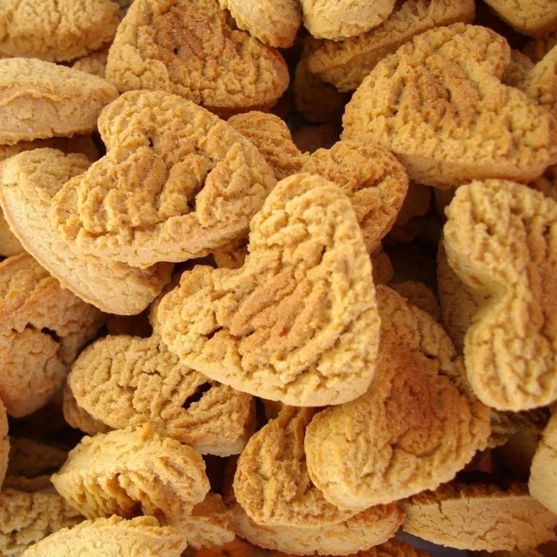 A close-up of Urban Dog Barkery’s Heart Treats shows several heart-shaped, handmade dog treats with a textured surface, stacked together.