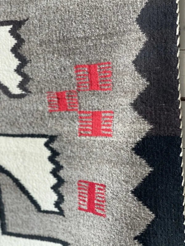 Close-up of a Klagetoh Rug Circa 1950 by Vintage, showcasing geometric black, white, and gray patterns with four small red rectangles near the center.