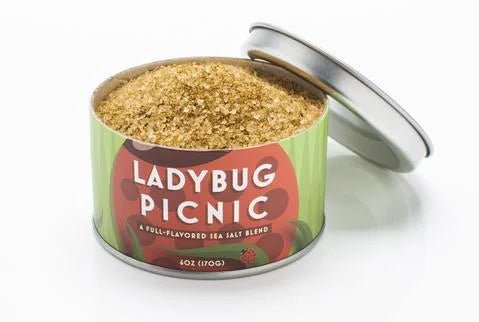 The Ladybug Picnic Sea Salt by Beautiful Briny Sea comes in a metal tin, its lid ajar to display the coarse, full-flavored blend—ideal for elevating any outdoor picnic.