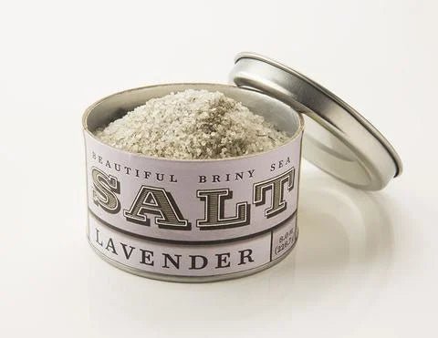 An open tin labeled "Lavender Sea Salt | Beautiful Briny Sea" from Beautiful Briny Sea is filled with gourmet lavender sea salt and rests on a white background.
