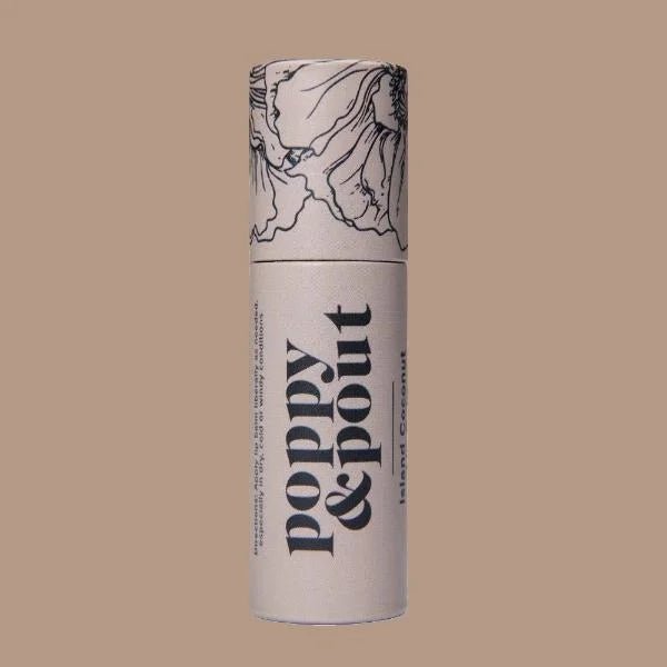 A beige cylindrical container labeled "Poppy & Pout" with floral line art and "Island Coconut" rests on a matching background, highlighting this cruelty-free, natural Lip Balm by Poppy & Pout.
