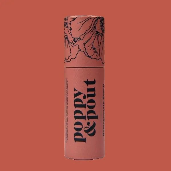 A cylindrical tube of Poppy & Pout Lip Balm in Pomegranate Peach stands against a matching background, with floral sketches decorating the cap.