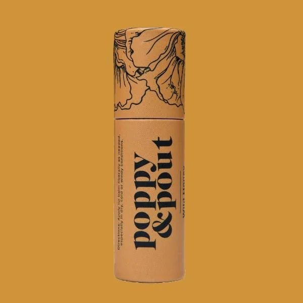 A cylindrical tan tube of "Lip Balm | Poppy & Pout" by Poppy & Pout, featuring a floral illustration on the cap, is shown against a mustard background.
