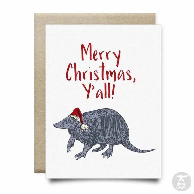 The Merry Christmas Yall Card by Anvil Cards features an armadillo in a Santa hat with "Merry Christmas, Y'all!" in red on linen paper; A2 size and blank inside for your message.