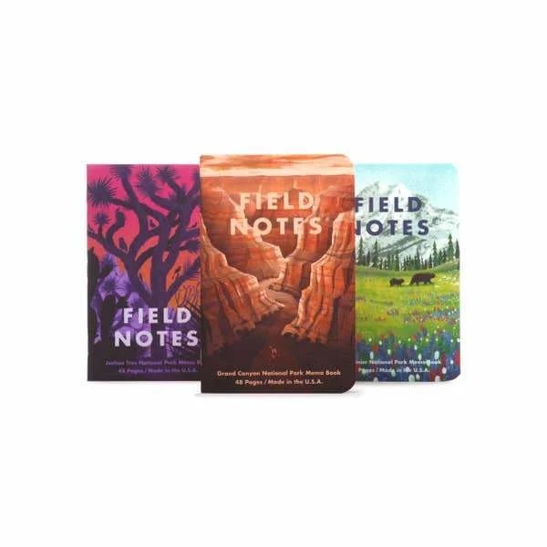 Three National Parks Pack memo books by Field Notes, each with a unique park design, stand upright in a row against a white background.
