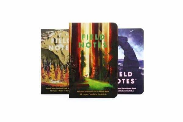 Three Field Notes National Parks Pack notebooks by Field Notes, each with a unique park-themed cover, are displayed upright against a white background.