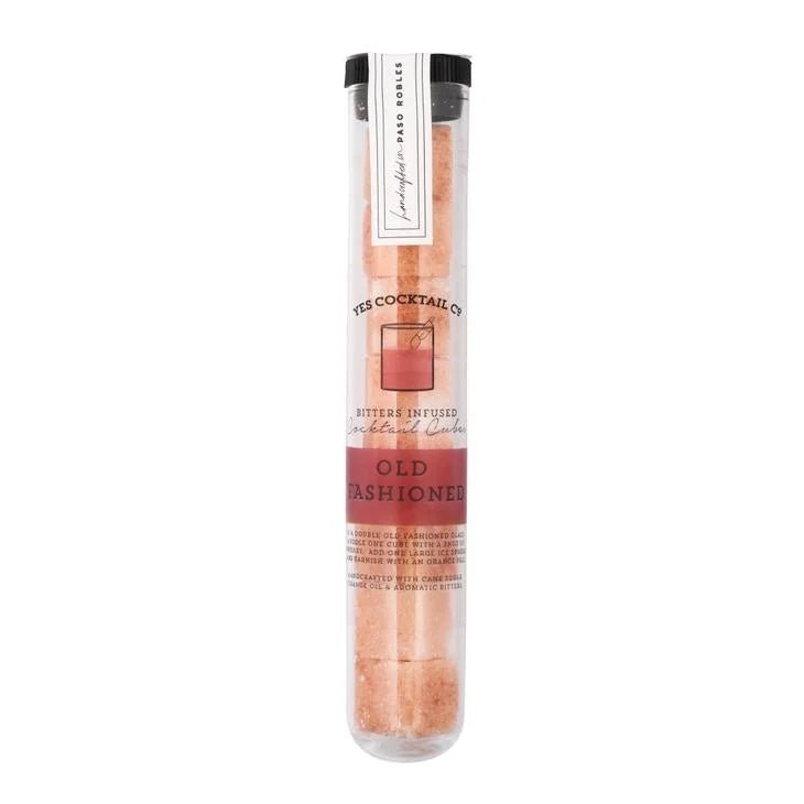 A clear test tube holds pink organic cane sugar cubes infused with bitters, labeled "Old Fashioned Cocktail Cubes" by Yes Cocktail Co.